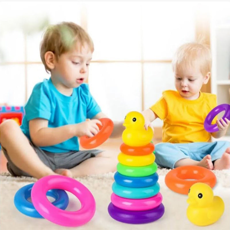 Two toddlers playing with a colorful stacking rings toy featuring a yellow duck on top, helping to develop motor skills and hand-eye coordination.